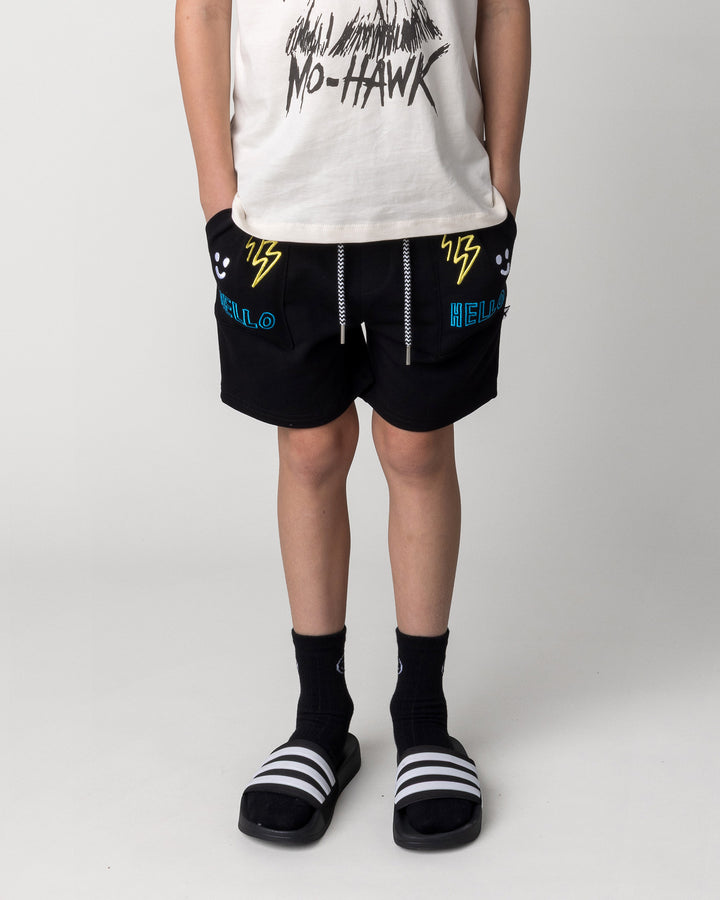 Kid wearing the Badges Short in black, front view close up