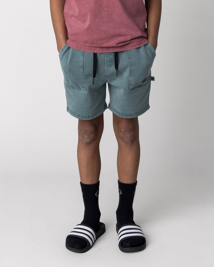 Kid wearing the Blasted Track Short in forest wash, front view close up