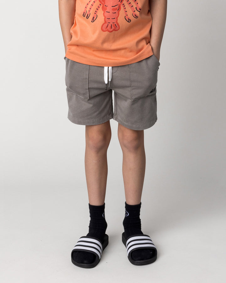 Kid wearing the Blasted Track Short in grey wash, front view close up