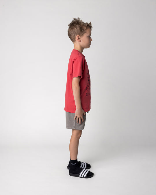 Kid wearing the Blasted Track Short in grey wash with the Werewolf Rockstar Tee in melon, side view