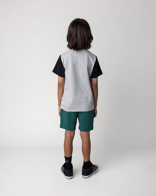 Kid wearing the Track Short in kelly green with the Patchwork Monster Tee in grey marle and black, back view