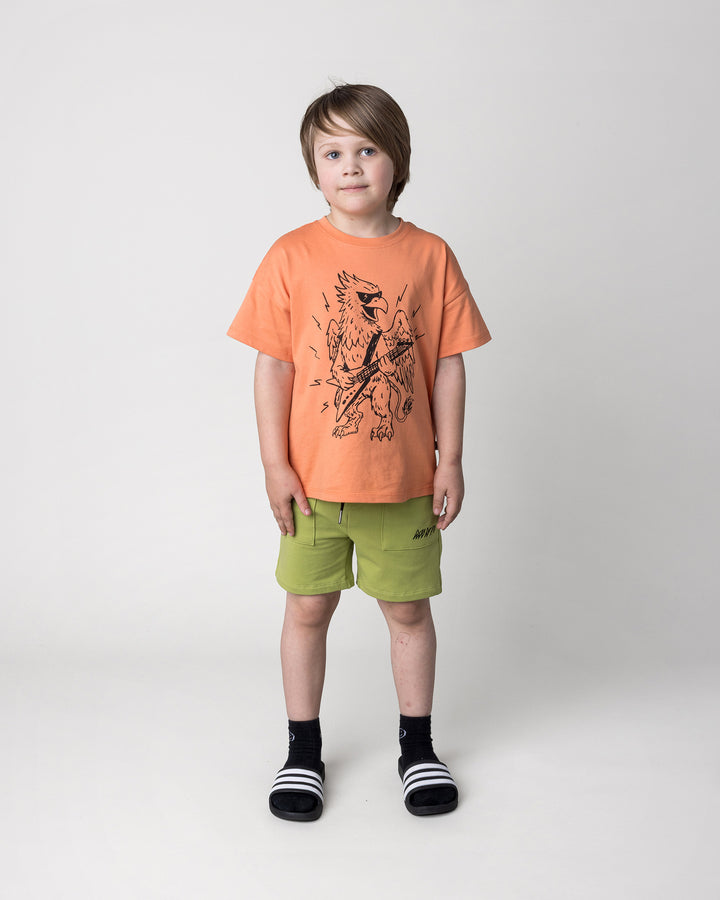 Kid wearing the Track Short in lime with the Rock Griffin Tee in light orange, front view
