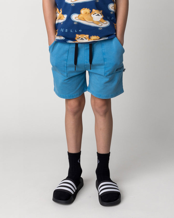 Kid wearing the Blasted Track Short in sky wash, front view close up