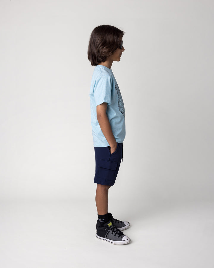Kid wearing the Deluxe Cargo Short in ink with the Boarding Bear Tee in blue marle, side view