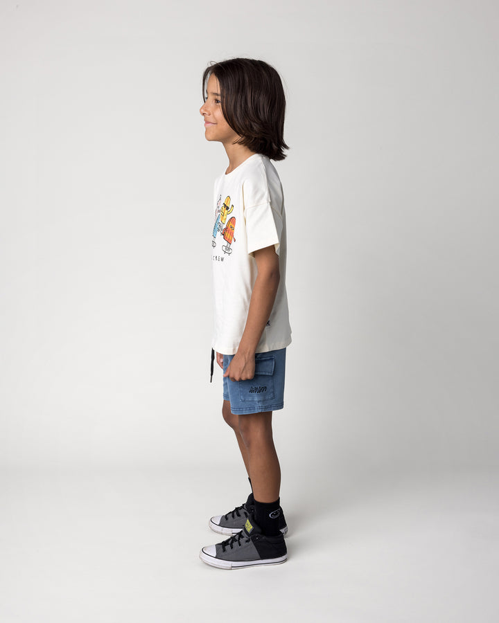 Kid wearing the Blasted Deluxe Cargo Short in midnight wash with the Cool Crew Tee in cream, side view