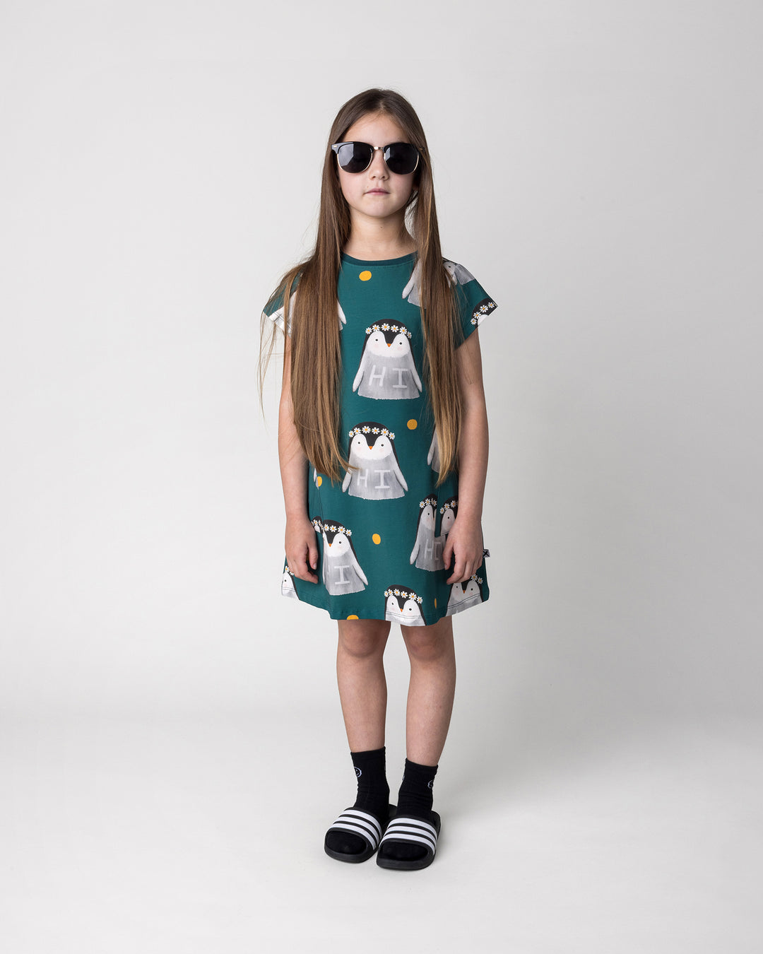 Kid wearing the Flower Penguin Dress in dark green, front view