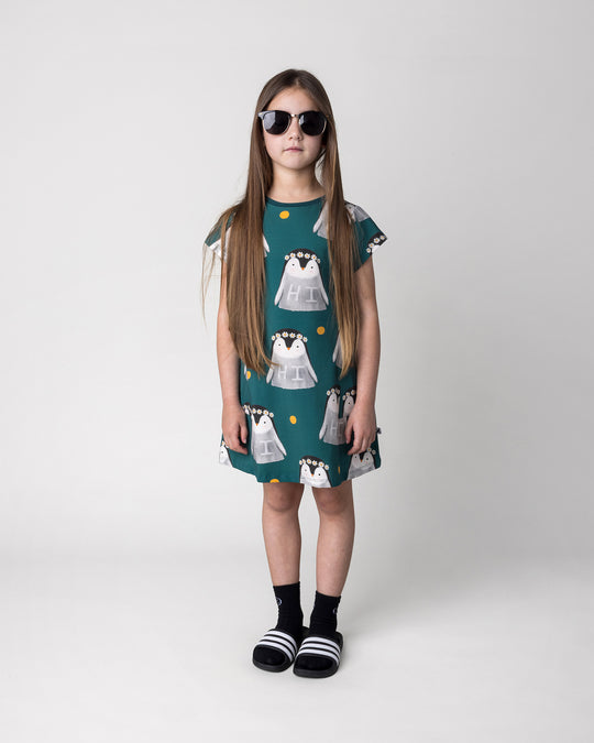 Kid wearing the Flower Penguin Dress in dark green, front view