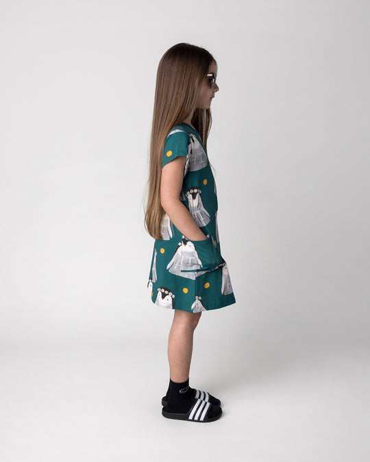 Kid wearing the Flower Penguin Dress in dark green, side view