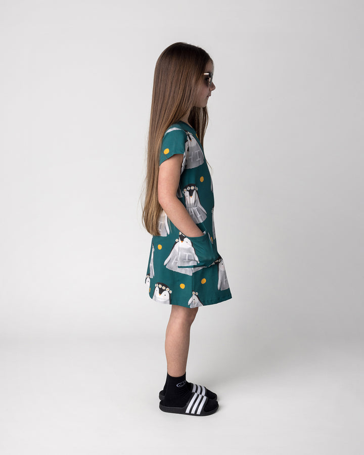 Kid wearing the Flower Penguin Dress in dark green, side view