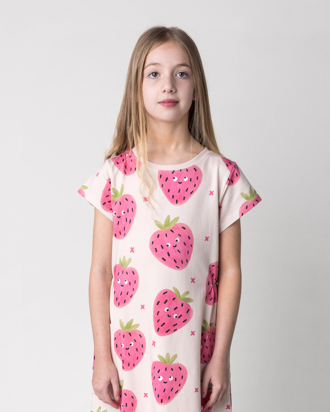 Close up of the Happy Strawberry Dress in cream on a kid, front view