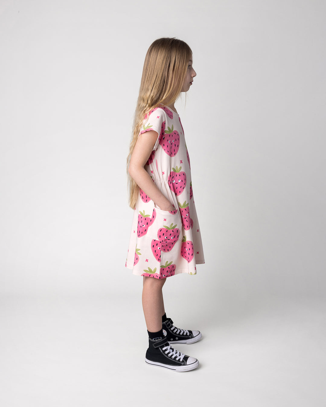 Kid wearing the Happy Strawberry Dress in cream, side view