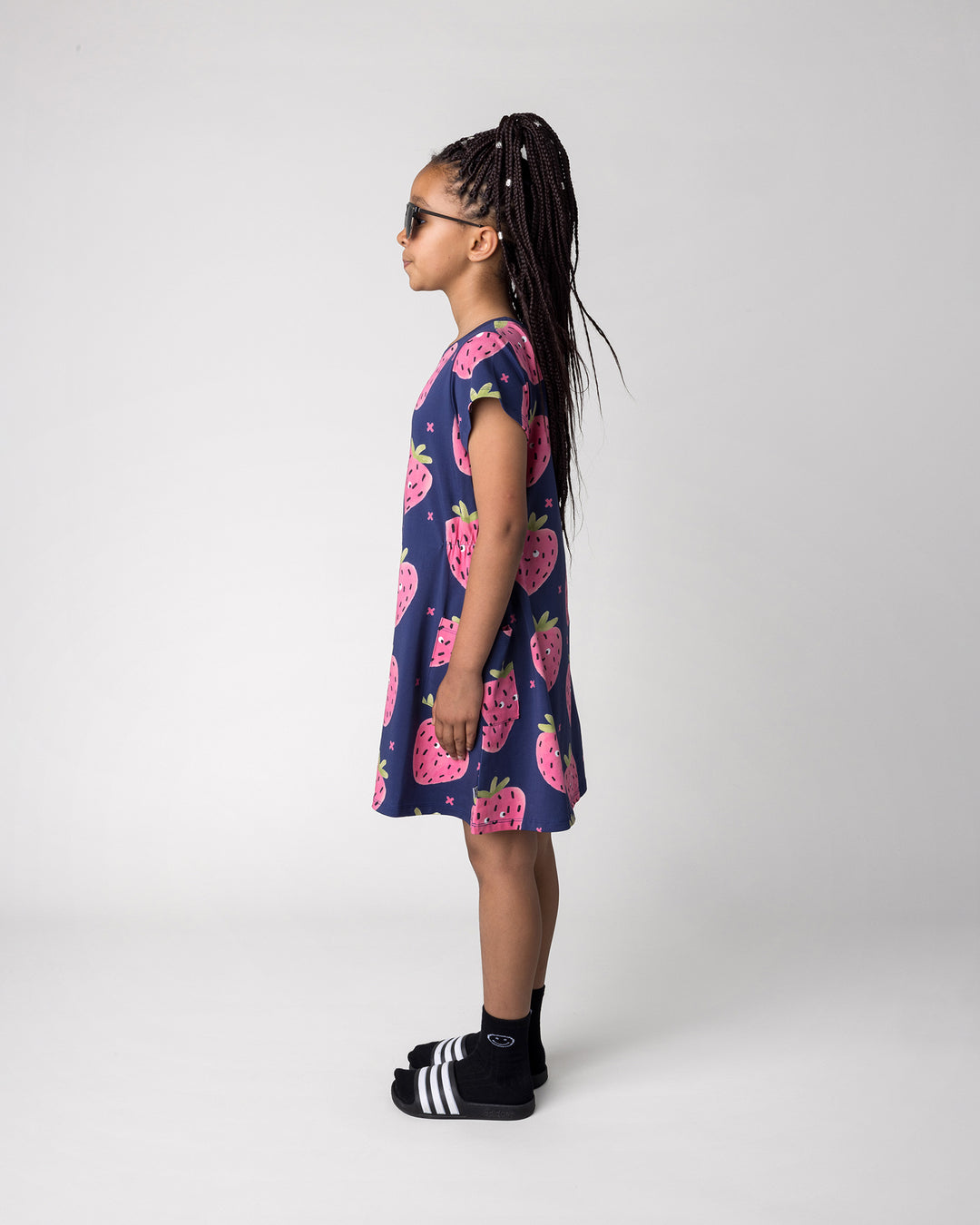 Kid wearing the Happy Strawberry Dress in turquoise, side view