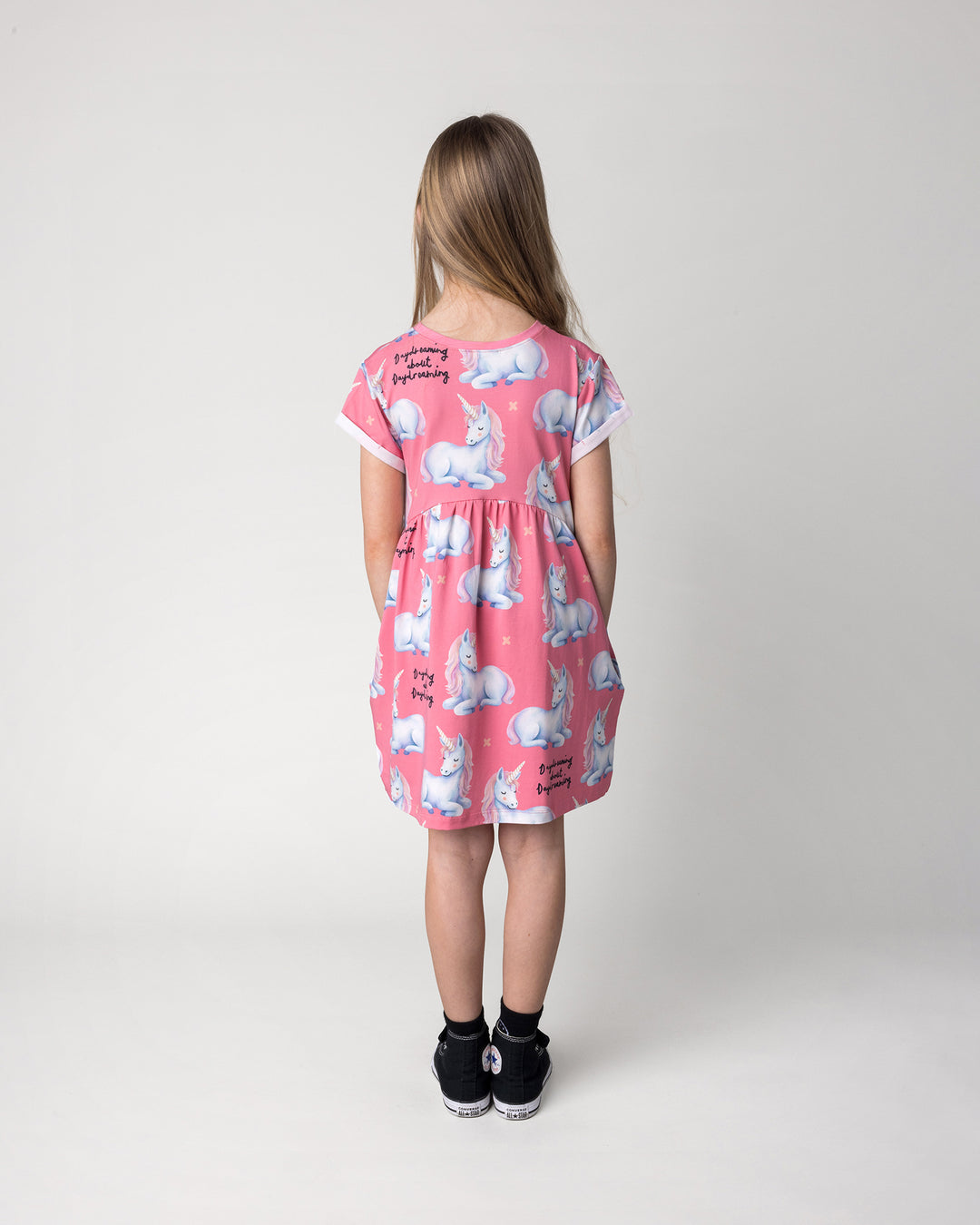 Kid wearing the Daydreaming Unicorn Dress in candy, back view