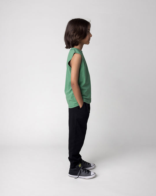 Kid wearing the Hi Pigeon Sleeveless Tee in turf wash with the Studio Trackies in black, side view
