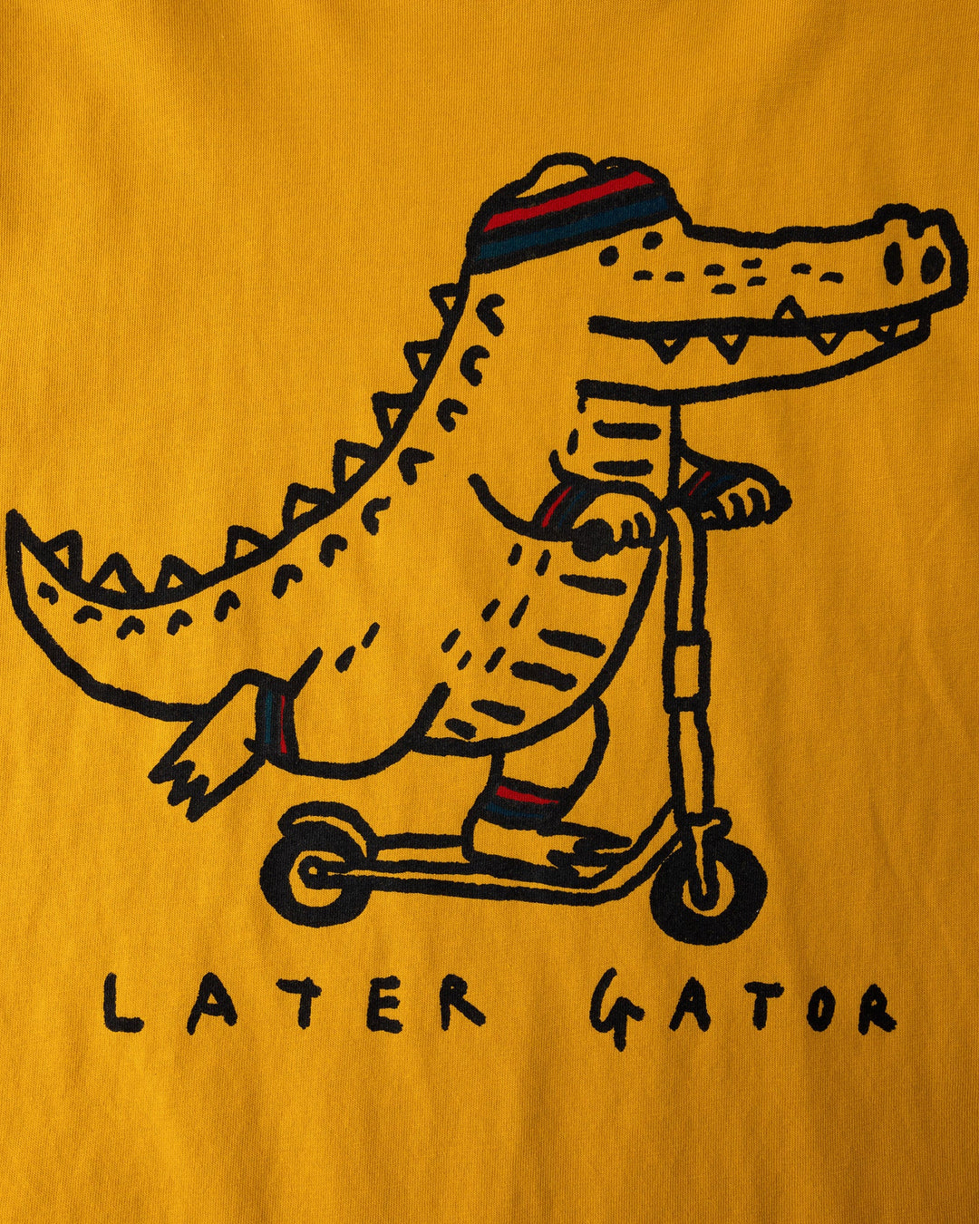 Close up of the Later Gator Sleeveless Tee print in mustard
