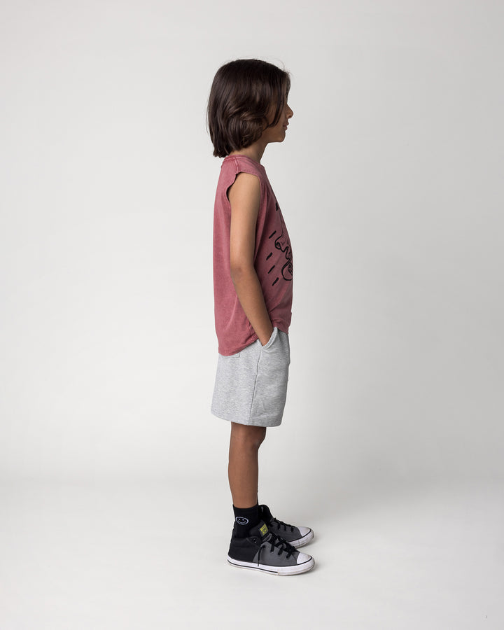 Kid wearing the Skate Ghost Sleeveless Tee in burnt red wash with the Smile Short in grey marle, side view