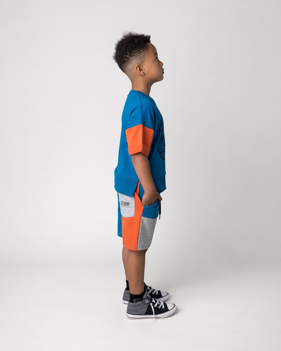 Kid wearing the Sliced Short in teal, orange and grey marle with the Chill Sloth Short Sleeve Crew in teal, orange and grey marle, side view