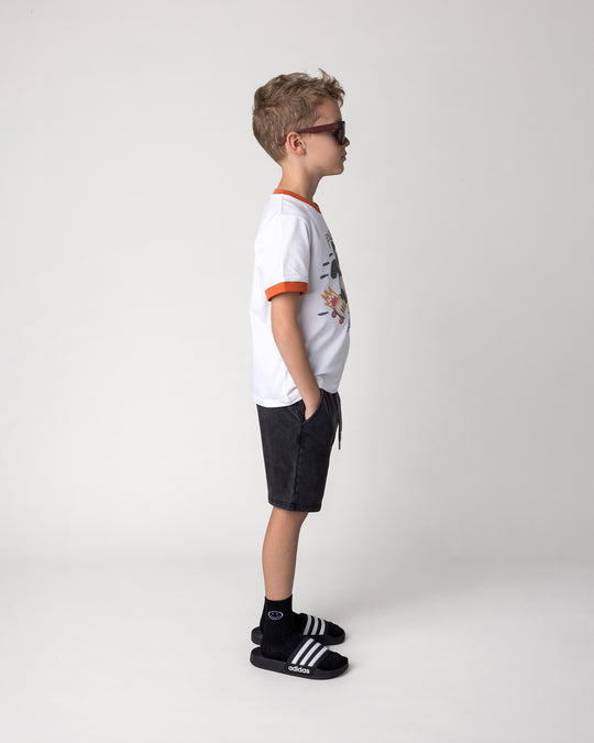 Kid wearing the Blasted Icon Short in black wash with the Fast Panda Tee in white and orange, side view