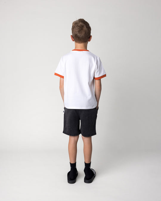 Kid wearing the Blasted Icon Short in black wash with the Fast Panda Tee in white and orange, back view