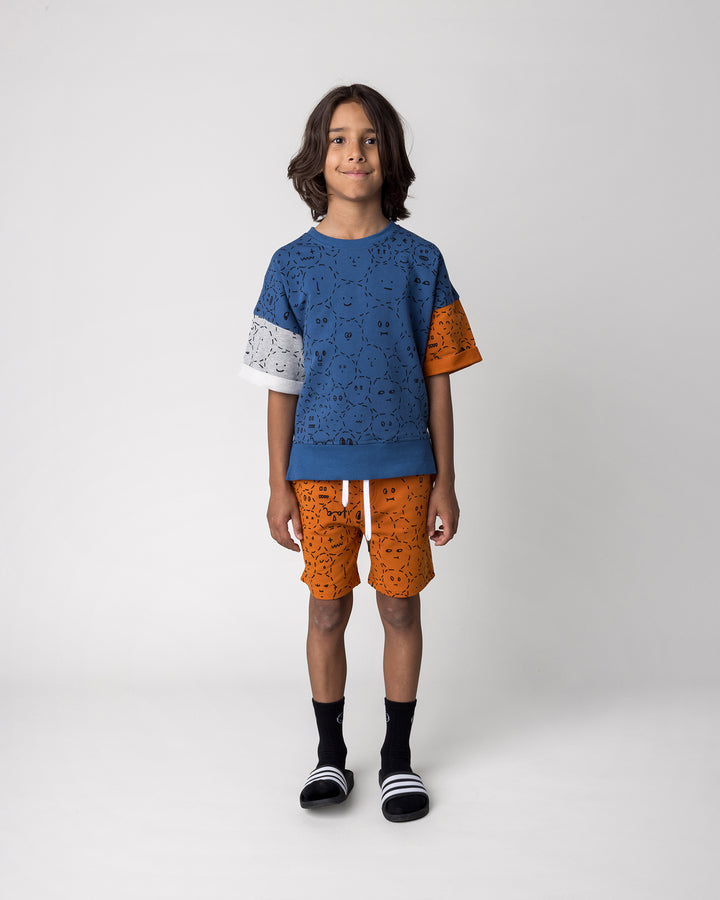 Kid wearing the Different Faces Short in burnt orange with the Different Faces Short Sleeve Crew in navy, grey marle and orange, front view