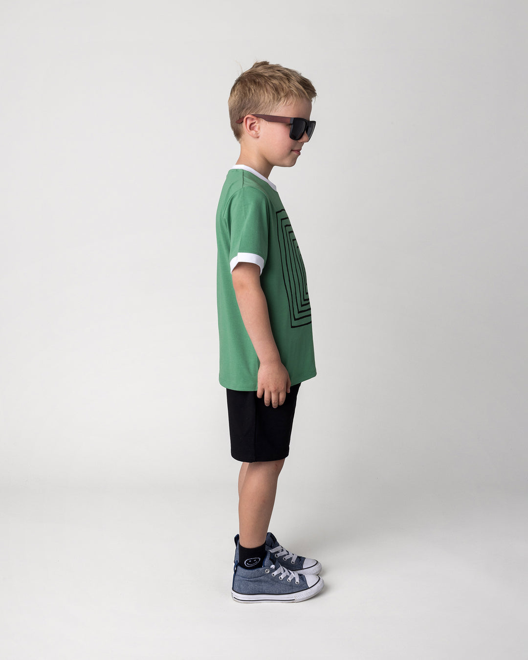 Kid wearing the Hero Short in black with the Hidden Panda Tee in turf and white, side view
