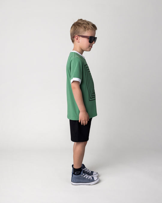 Kid wearing the Hero Short in black with the Hidden Panda Tee in turf and white, side view