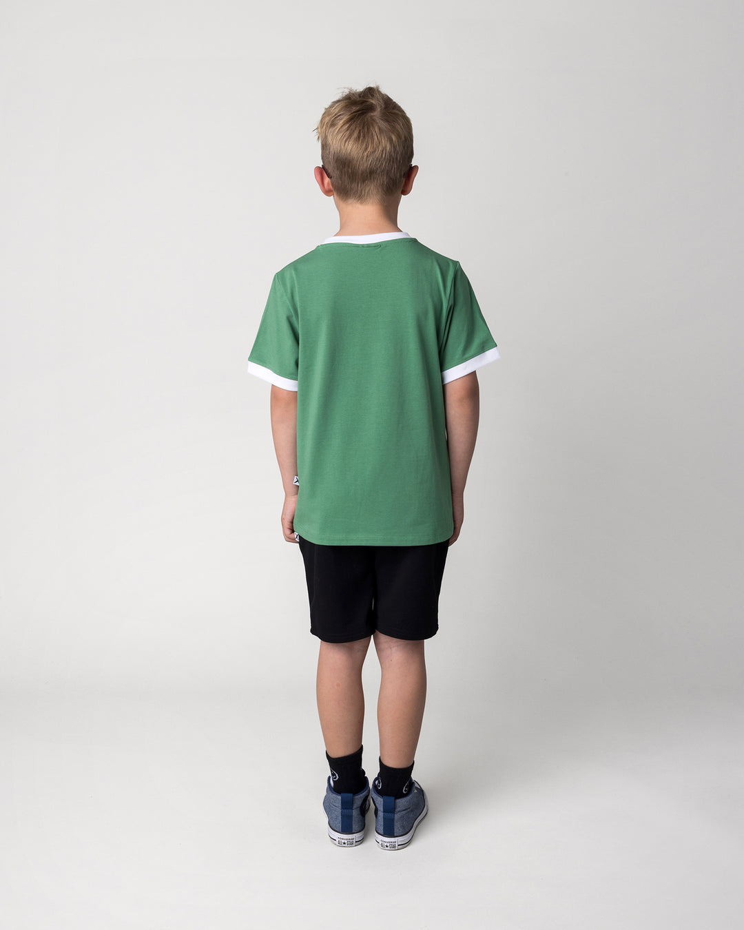 Kid wearing the Hero Short in black with the Hidden Panda Tee in turf and white, back view