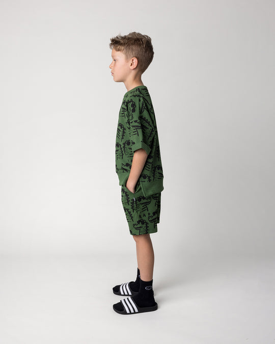 Kid wearing the Rad Croc Short in green with the Rad Croc Short Sleeve Crew in green, side view