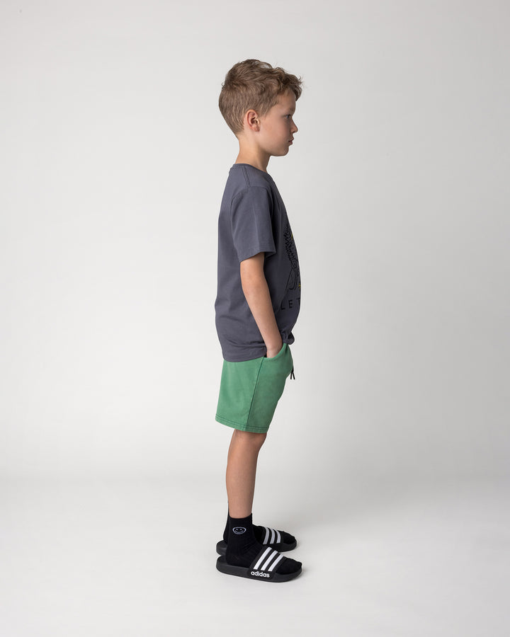 Kid wearing the Blasted Icon Short in turf wash with the Werewolf Rockstar Tee in dark grey, side view