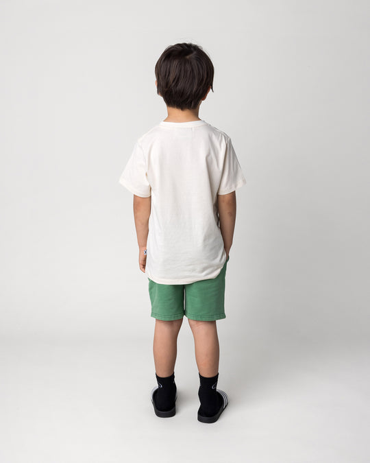 Kid wearing the Blasted Icon Short in turf wash with the Taco Saurus Tee in cream, back view