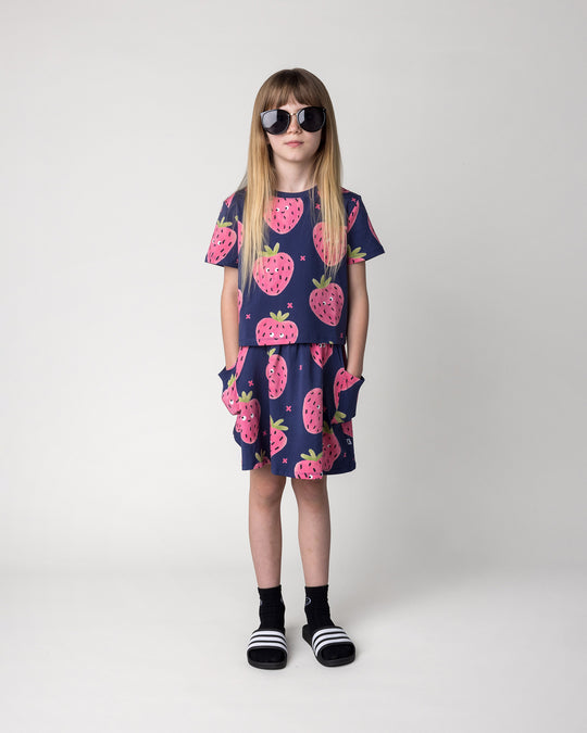 Kid wearing the Happy Strawberry Cropped Tee in turquoise with the Happy Strawberry Skirt in turquoise, front view