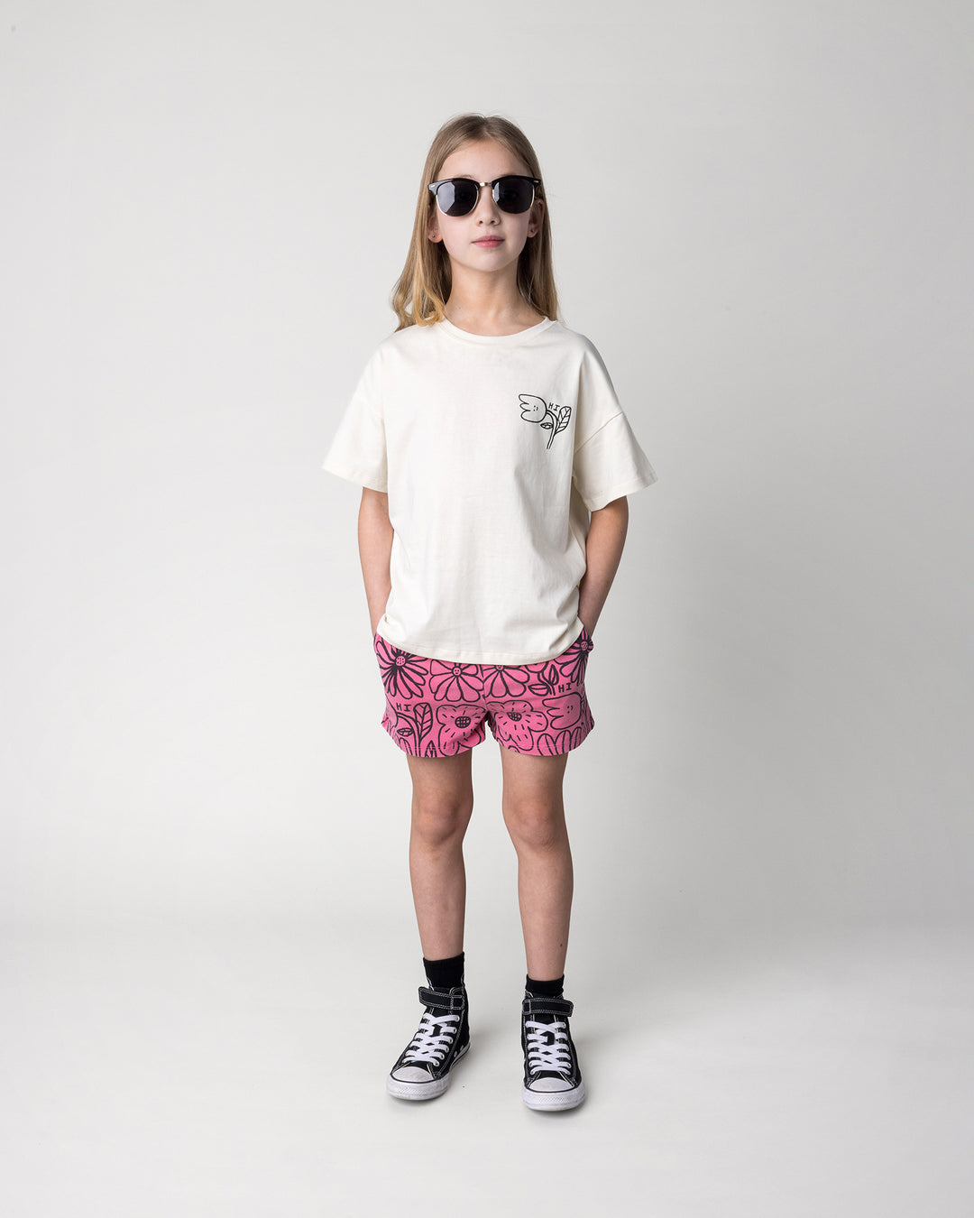 Kid wearing the Big Flowers Short in pink wash with the Pocket Flower Tee in cream, front view