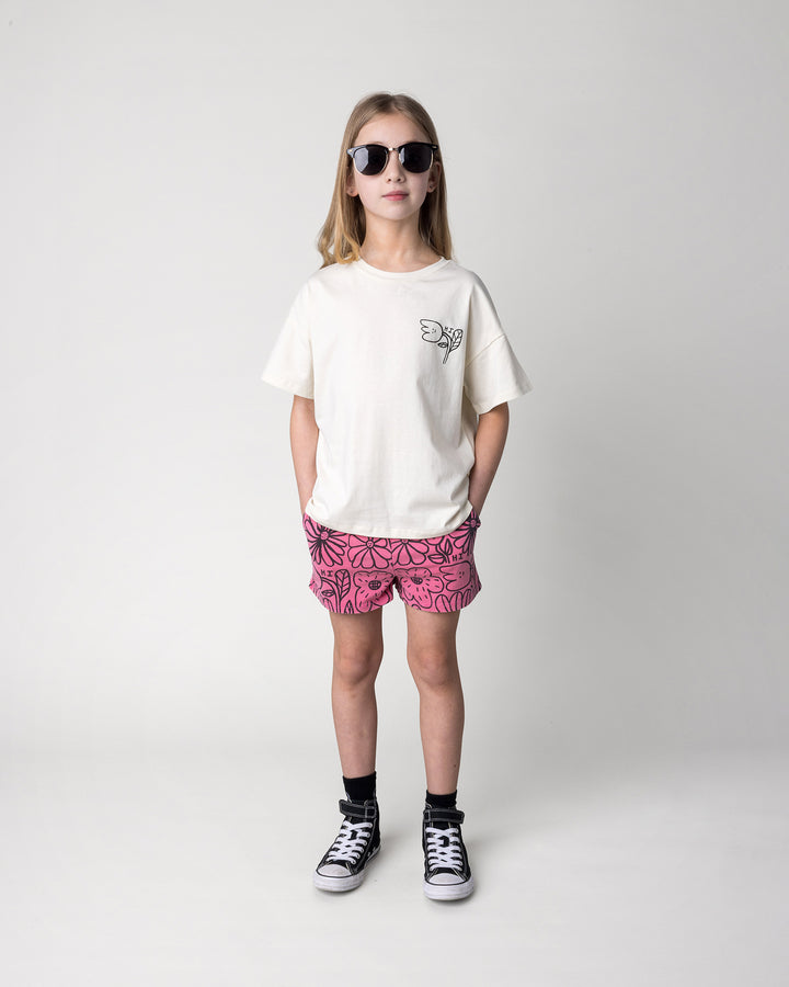 Kid wearing the Big Flowers Short in pink wash with the Pocket Flower Tee in cream, front view