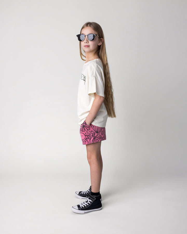 Kid wearing the Big Flowers Short in pink wash with the Pocket Flower Tee in cream, side view