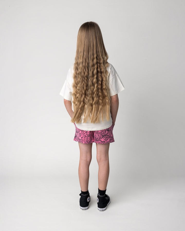 Kid wearing the Big Flowers Short in pink wash with the Pocket Flower Tee in cream, back view