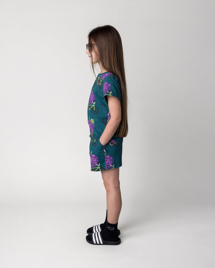 Kid wearing the Biking Grape Short in dark teal with the Biking Grape Tee in dark teal, side view