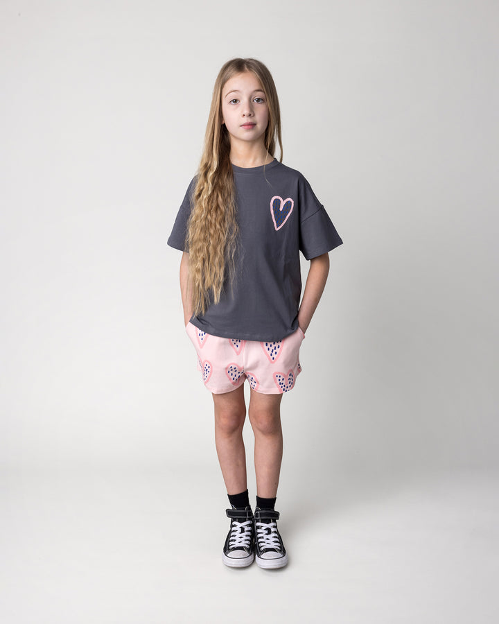 Kid wearing the Speckle Heart Short in pink with the Speckle Heart Tee in dark grey, front view