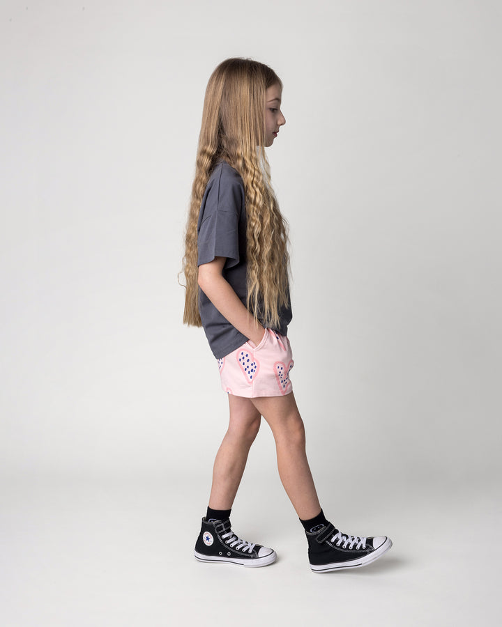 Kid wearing the Speckle Heart Short in pink with the Speckle Heart Tee in dark grey, side view