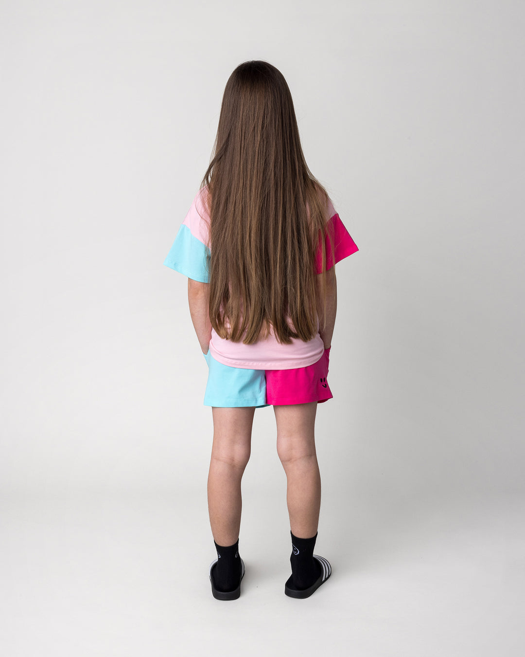 Kid wearing the Two Tone Short in hot pink and aqua with the Unicorn Club Tee in pink, hot pink and aqua, back view