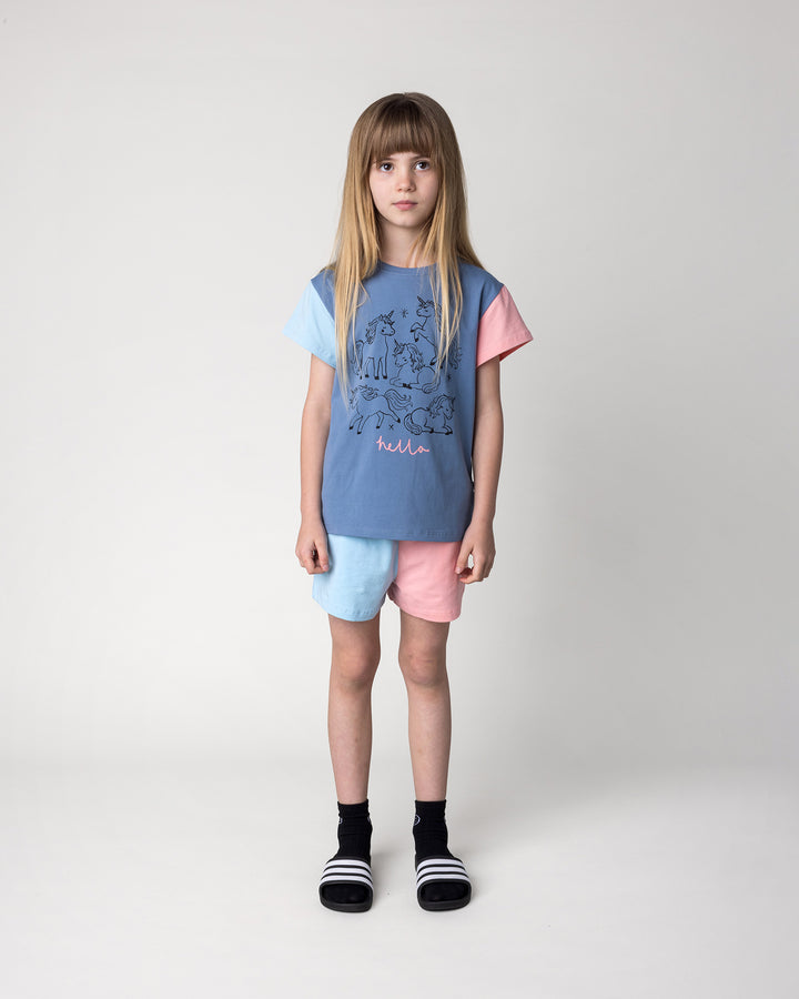Kid wearing the Two Tone Short in light blue and pink with the Hello Unicorns Tee in mid blue, light blue and pink, front view