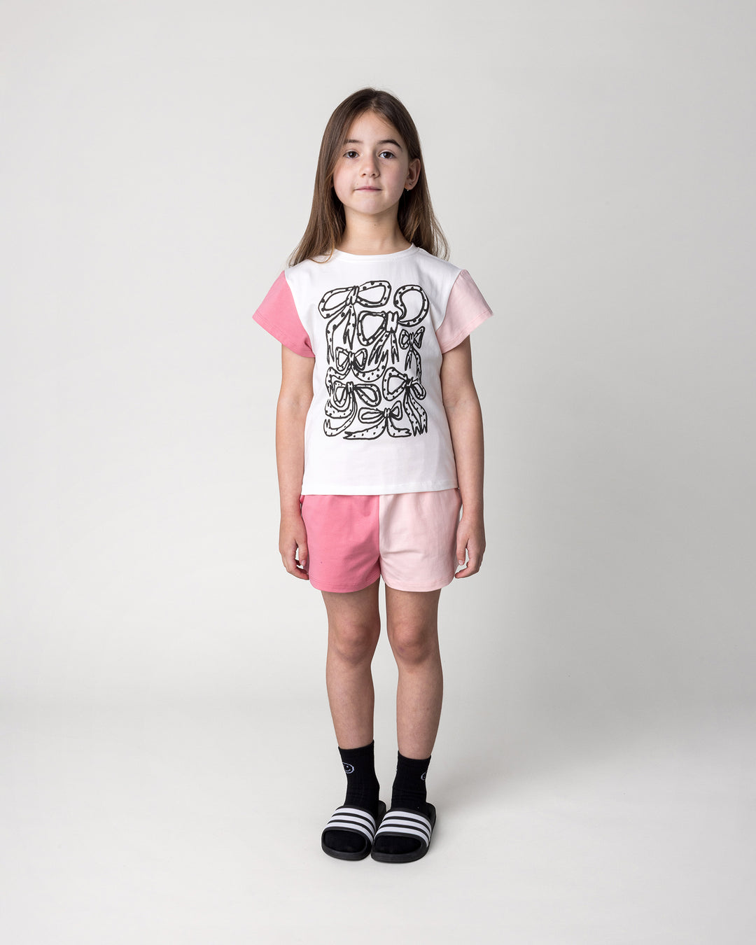 Kid wearing the Two Tone Short in pinks with the Messy Bows Tee in white and pinks, front view