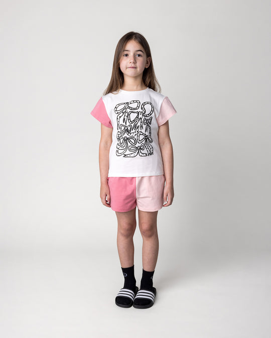 Kid wearing the Two Tone Short in pinks with the Messy Bows Tee in white and pinks, front view