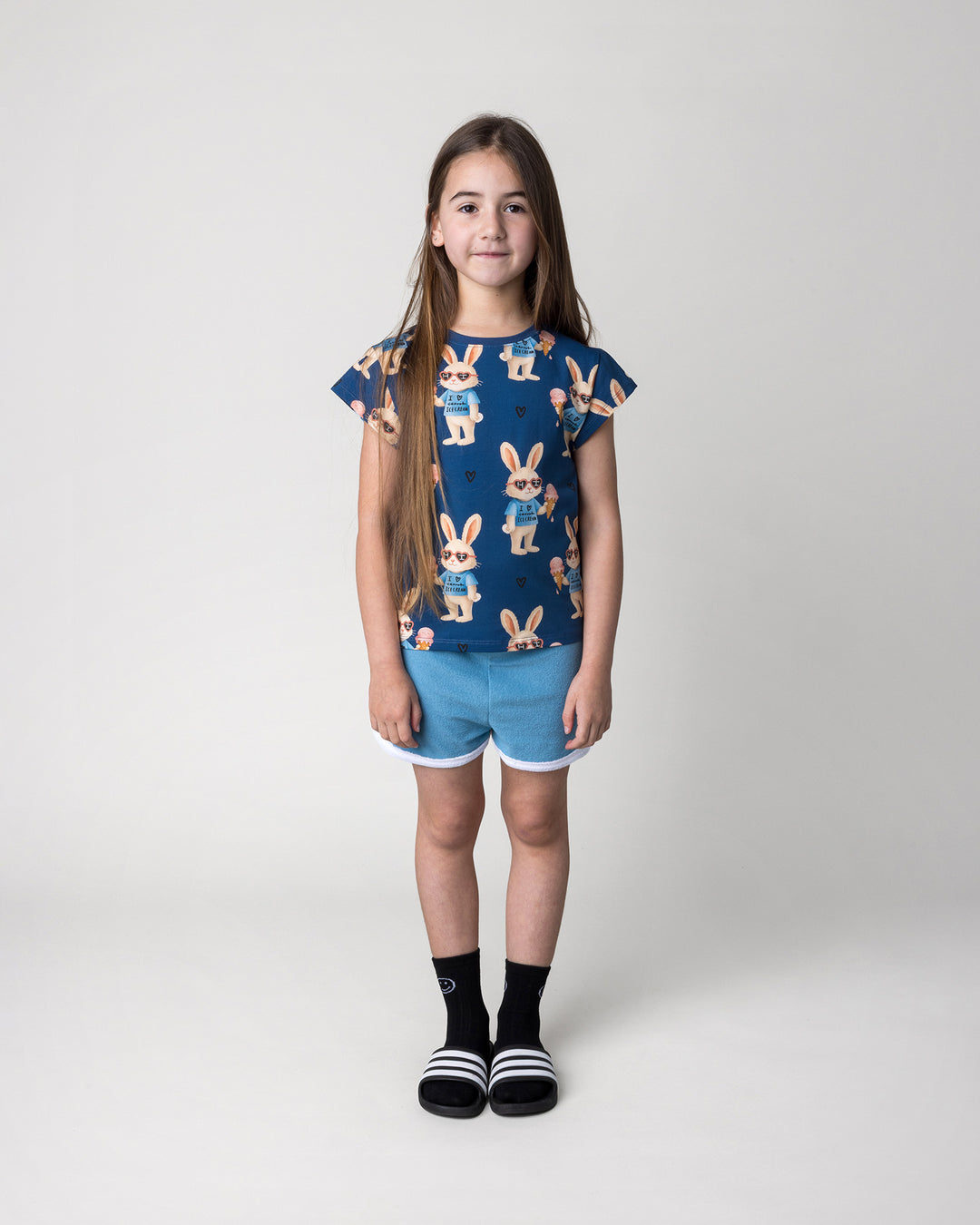 Kid wearing the Icecream Bunny Tee in blue with the Track Star Short in ocean, front view