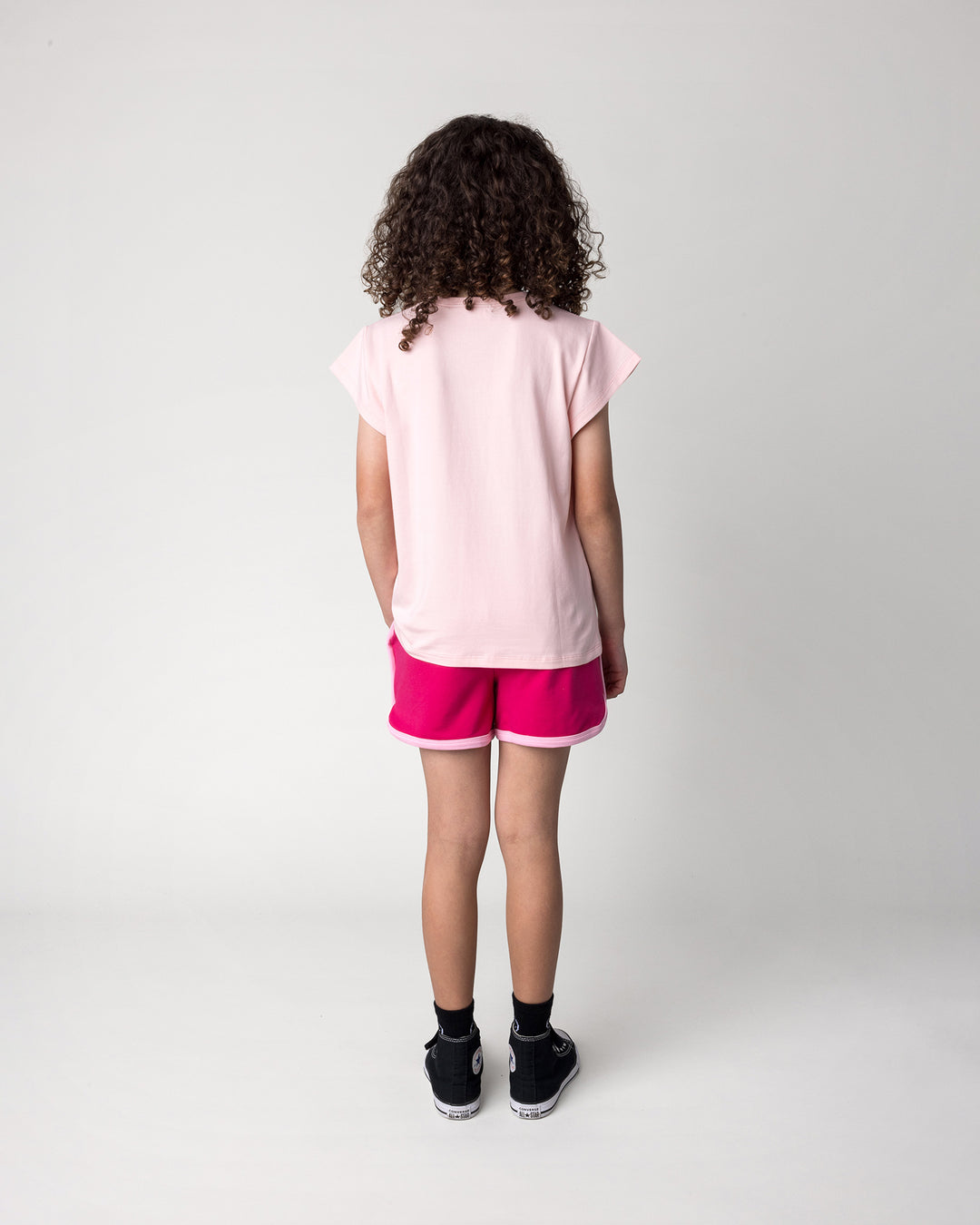 Kid wearing the Icecream Panda Tee in light pink with the Sprint Short in crimson and pink, back view