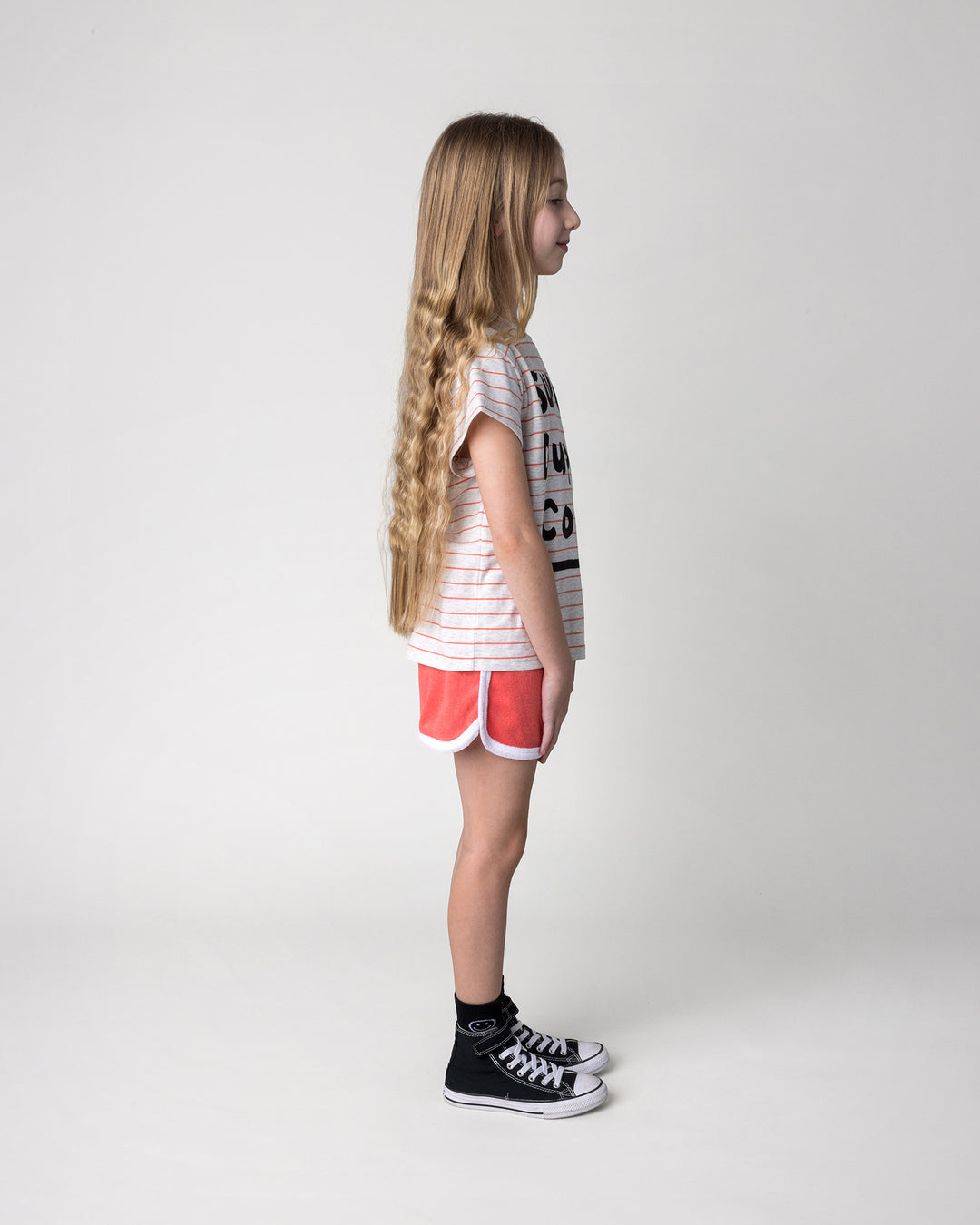 Kid wearing the Track Star Short in tangerine with the Super Duper Cool Tee in marle and coral stripe, side view