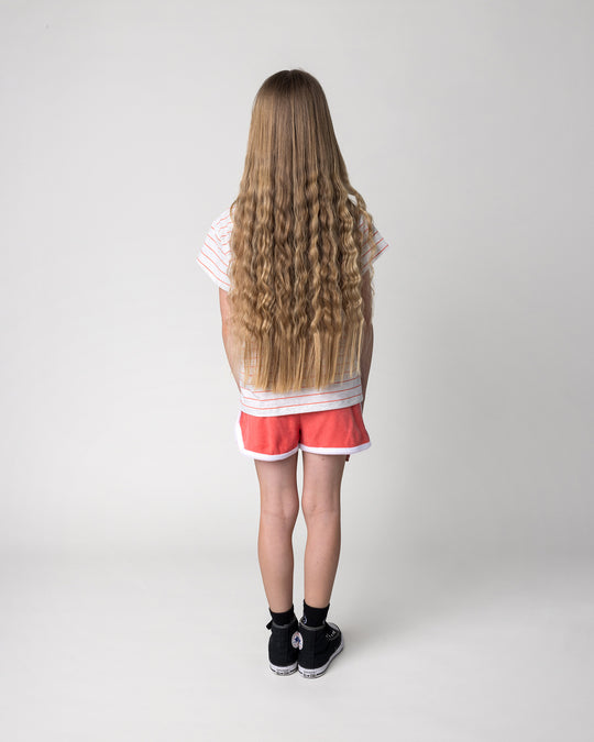 Kid wearing the Track Star Short in tangerine with the Super Duper Cool Tee in marle and coral stripe, back view