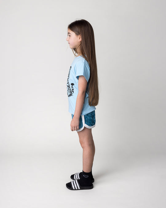 Kid wearing the Velvet Runner Short in light blue and cream with the Happy Tiger Tee in light blue, side view