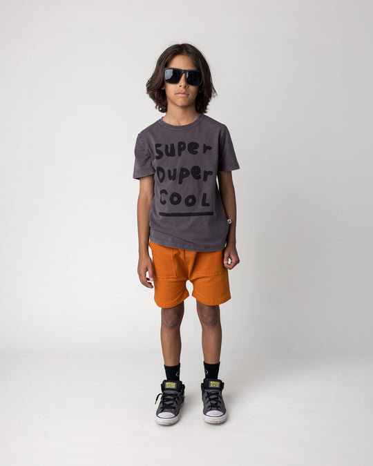 Kid wearing the Rib Pocket Short in burnt orange with the Super Duper Cool Tee in black wash, front view