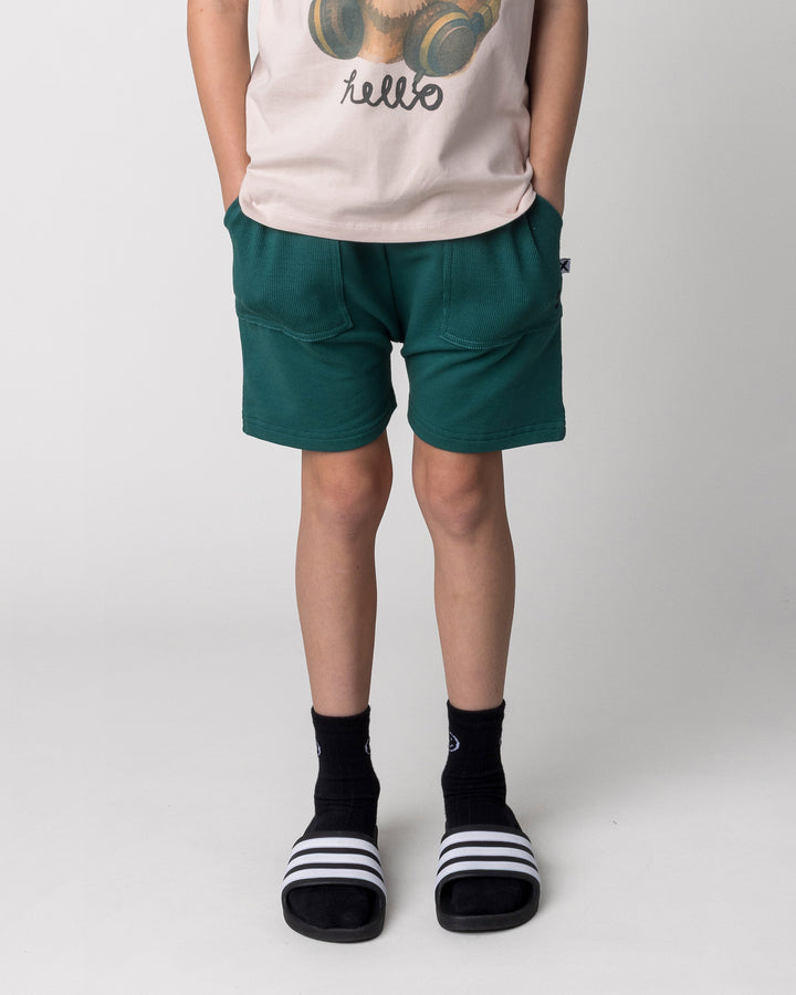 Kid wearing the Rib Pocket Short in kelly green, front view close up