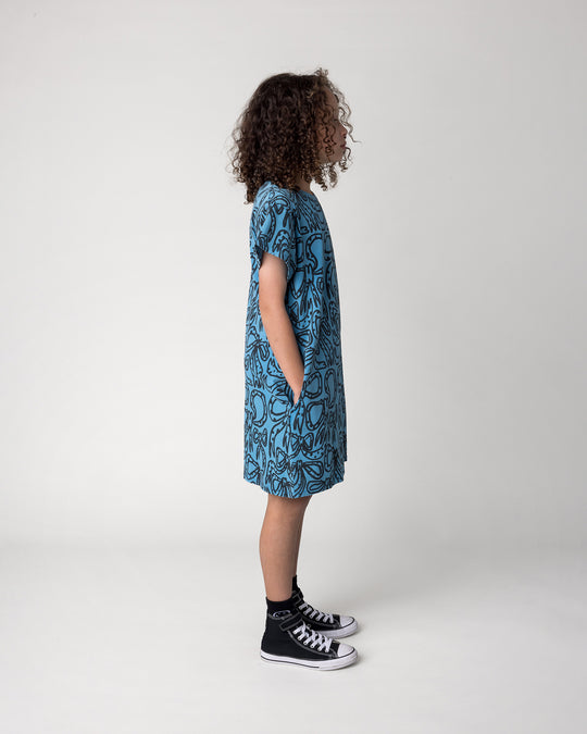 Kid wearing the Big Bows Dress in blue wash, side view